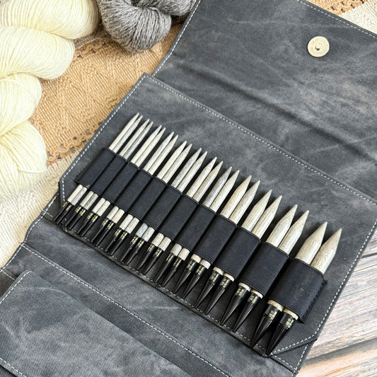 Set of Lykke Driftwood knitting needles in a gray case with yarn in the background