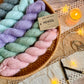 Colourful Baa Ram Ewe Mowool yarn skeins in a basket with a candle and decorative items on a wooden surface