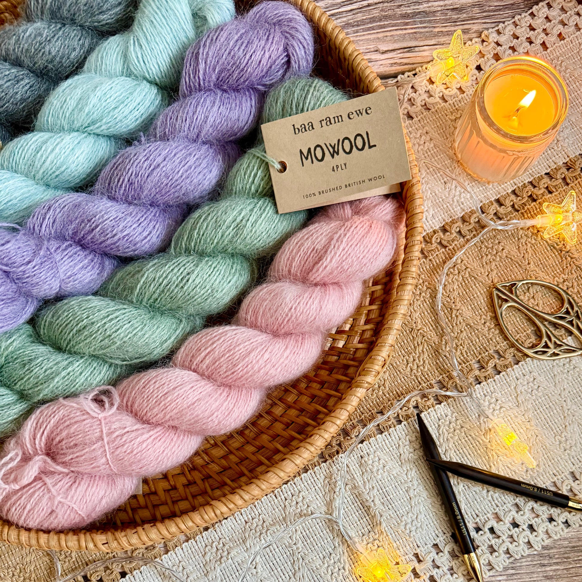 Colourful Baa Ram Ewe Mowool yarn skeins in a basket with a candle and decorative items on a wooden surface