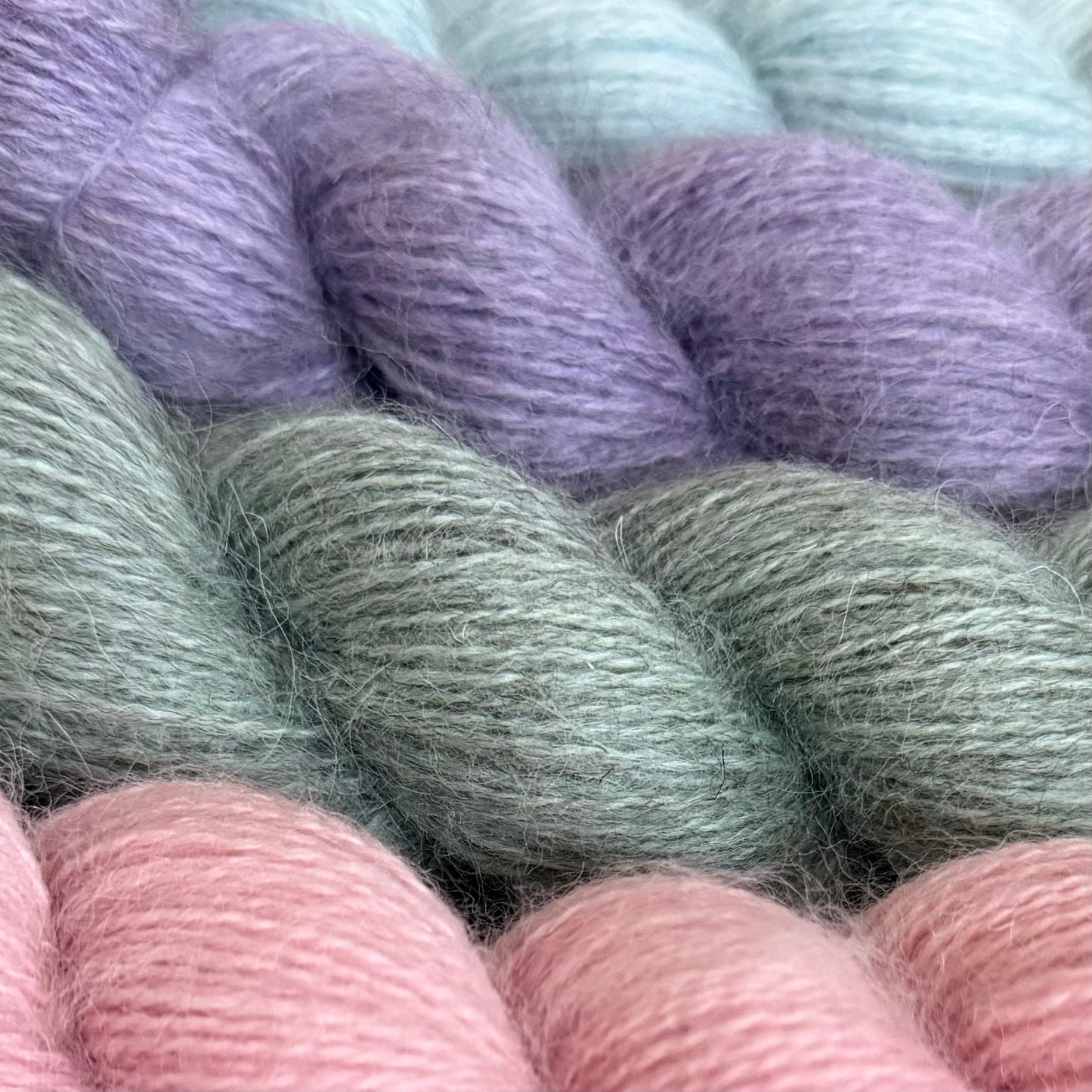 Close-up of pastel-coloured Baa Ram Ewe Mowool yarn skeins including purple, green, and pink.